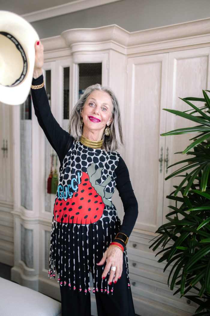 Honey Good, a woman with gray hair, holds a hat in the air with a smile on her face after finishing a negotiation class which gave her the skills to have difficult conversations.