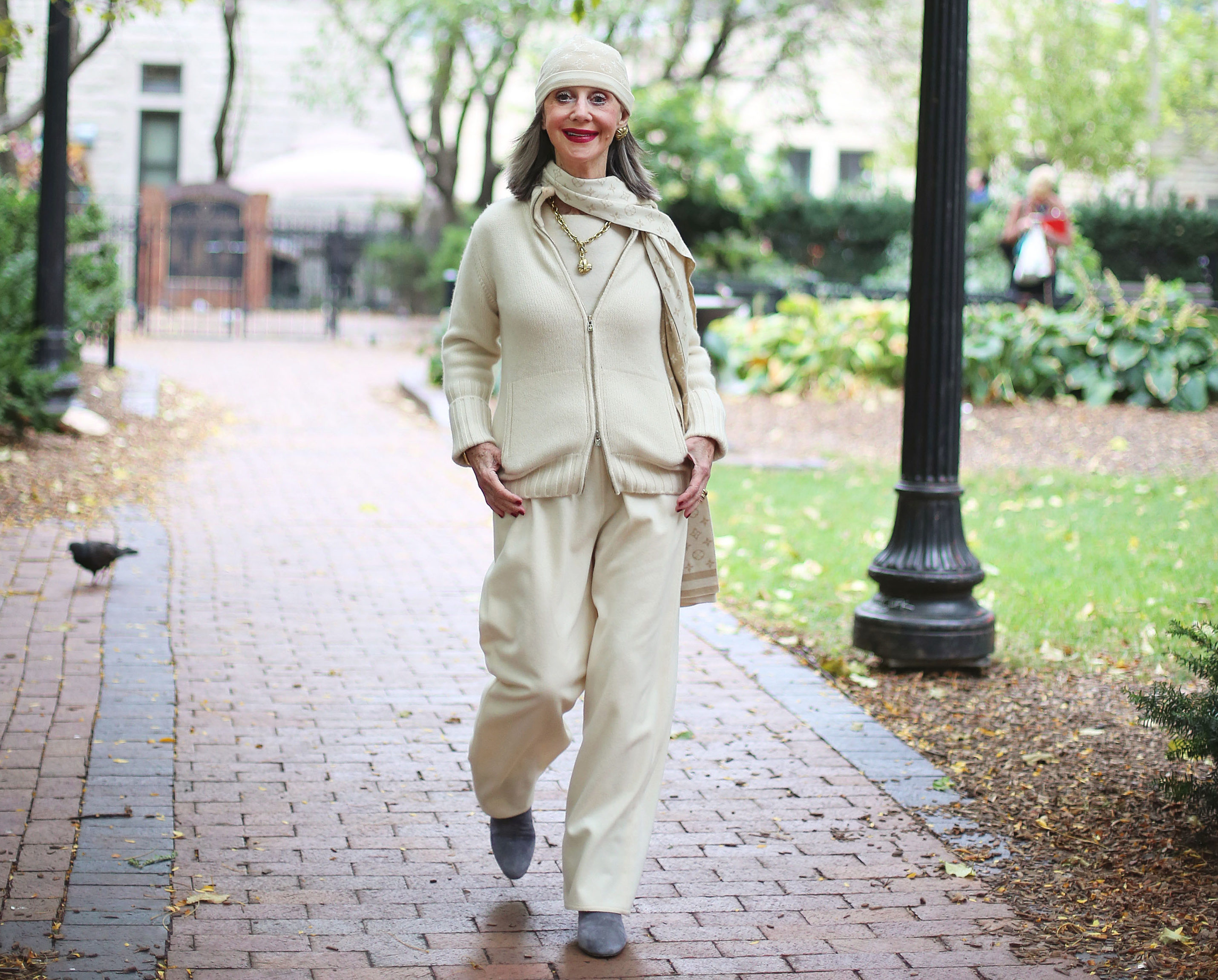 Image of Honey Good in a winter white look from head to to, walking on a brick sidewalk.