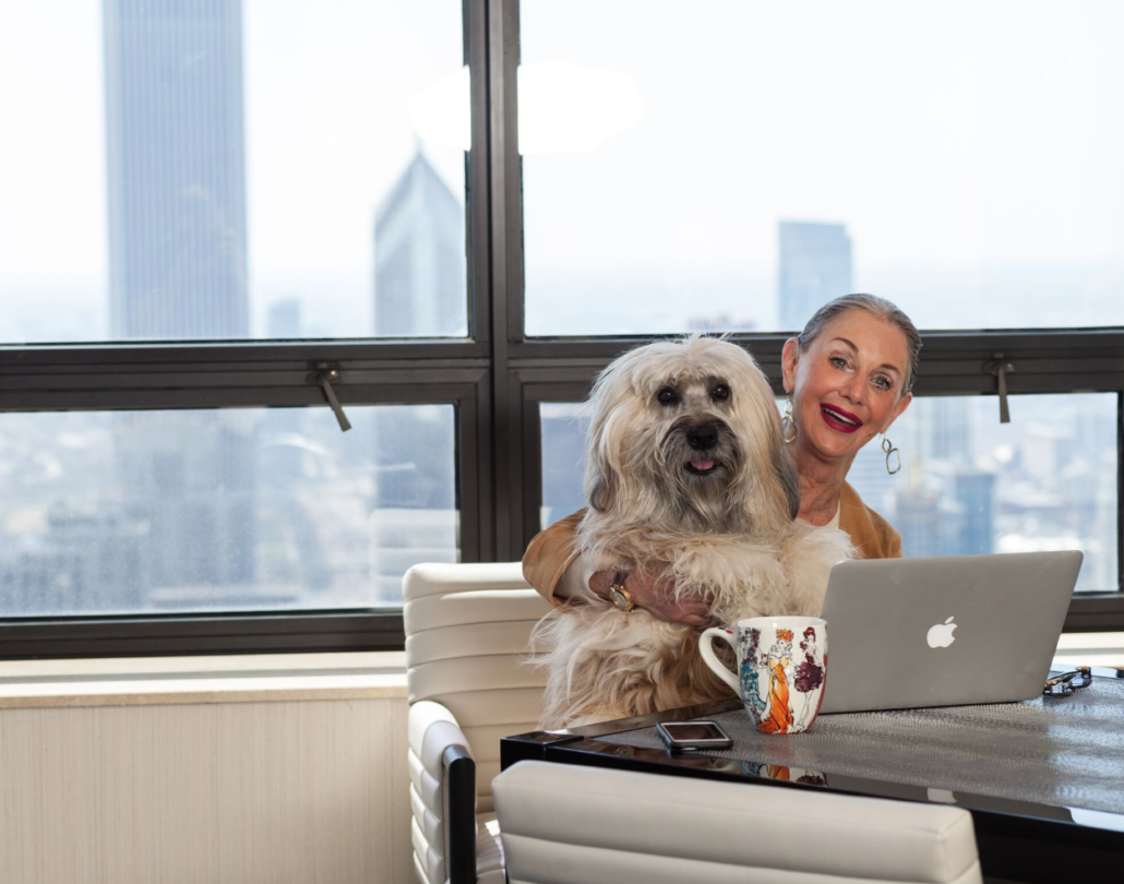 woman (Honey Good) Sitting at table with her dog on her lap. Having coffee and computer open