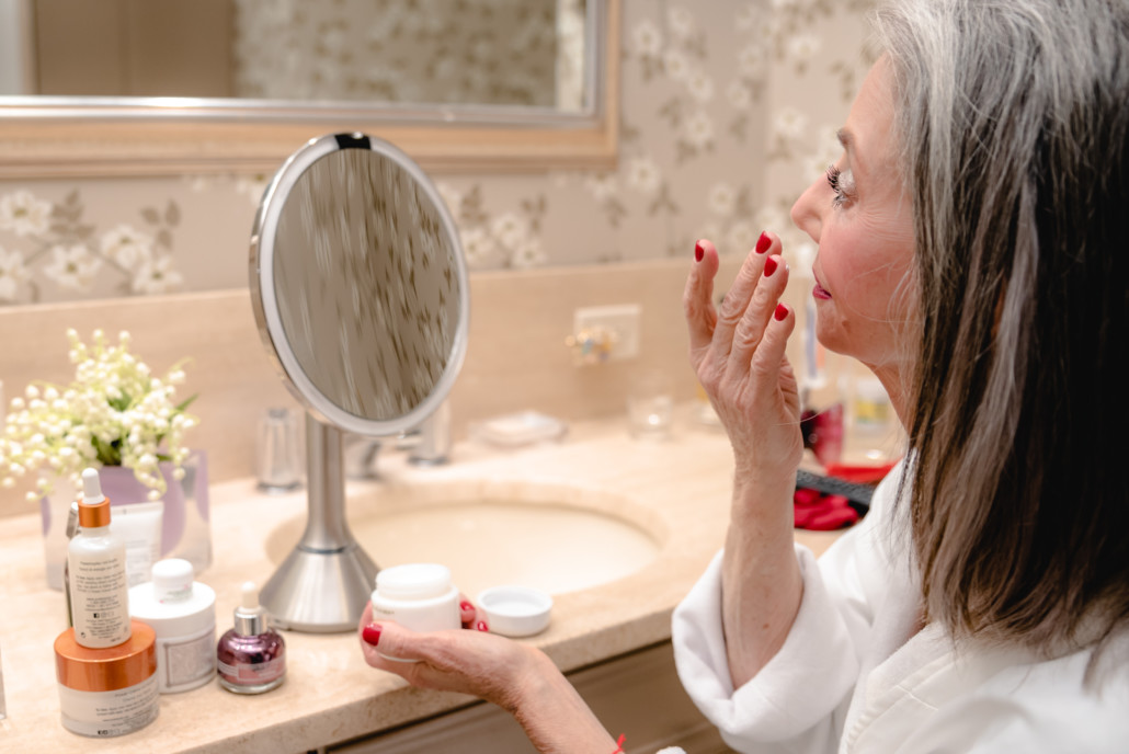 Beauty Routine older woman putting on face cream and prepping for mascara for women over 50