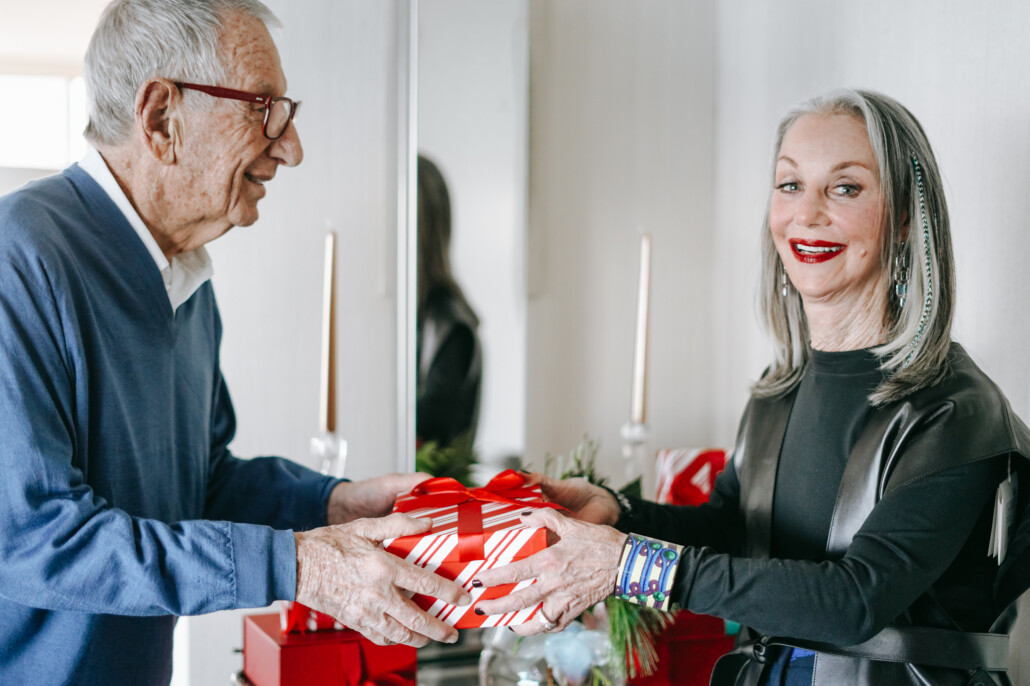 image of Honey and Shelly Good holding a gift wearing holiday makeup as honey shares her favorite lipsticks for women over 50