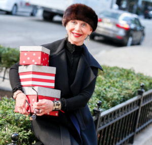 The Seasons of the Year, Honey Good smiling holding a stack of wrapped holiday gifts.