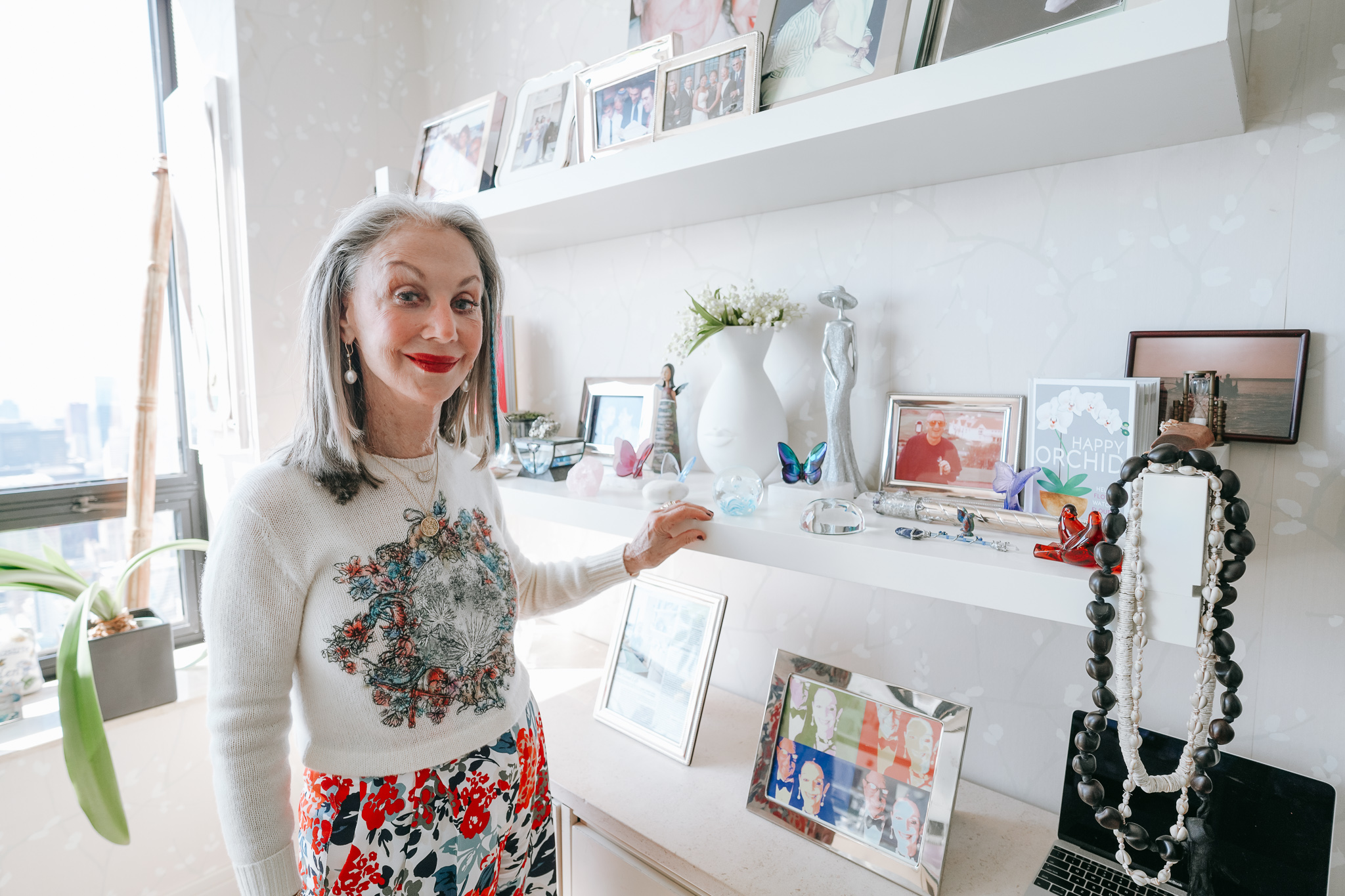 Image of Honey Good standing in her office showing off her keepsakes with a smile