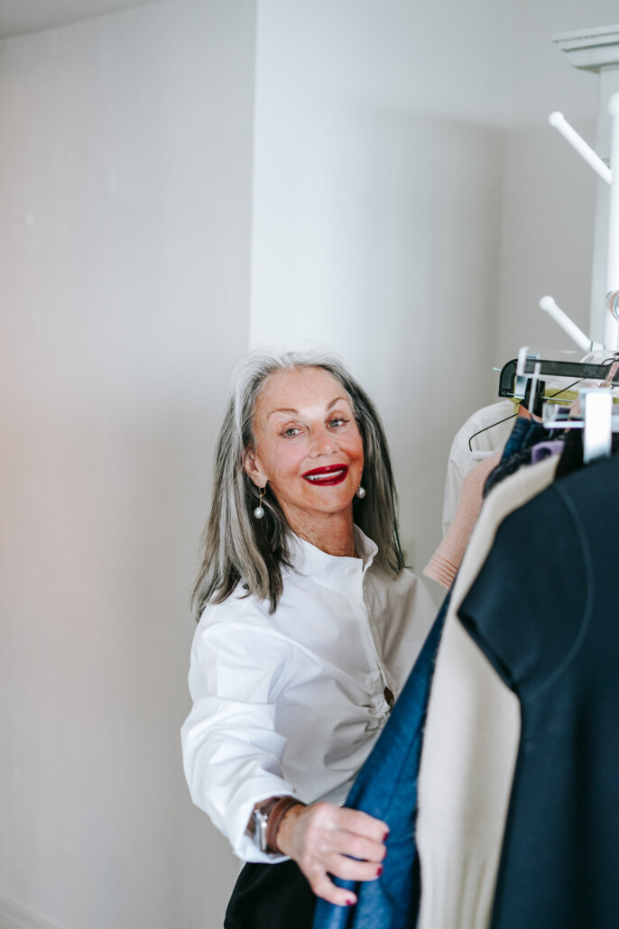 image of honey good looking for cocktail attire for women over 50 shifting through a rack of hung clothes