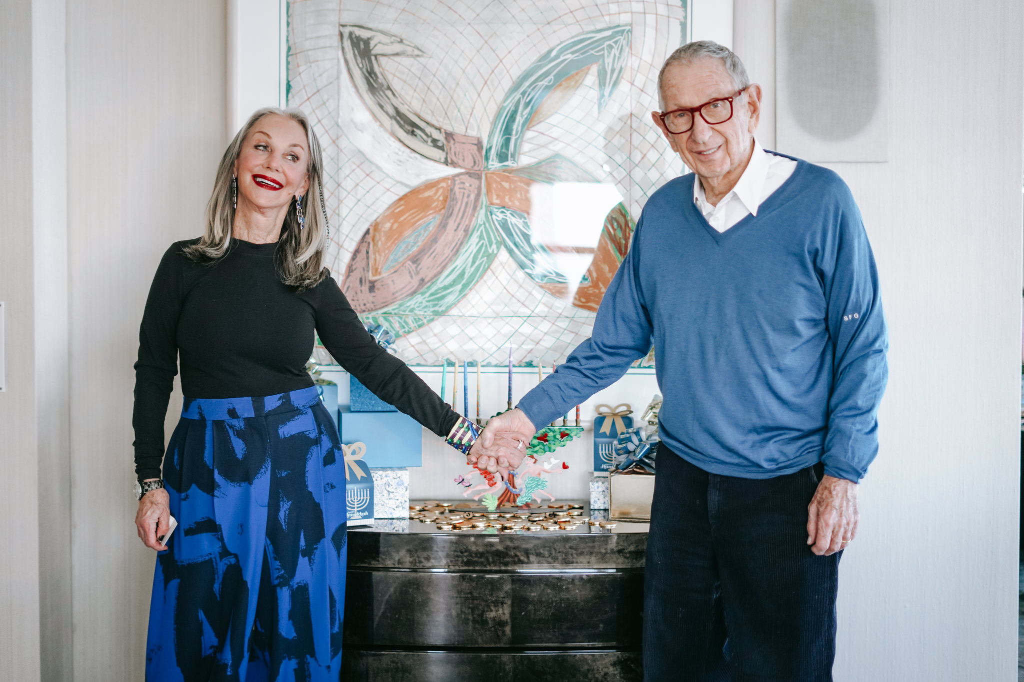Honey and Shelly celebrating Hanukkah and holding hands in front of the menorah